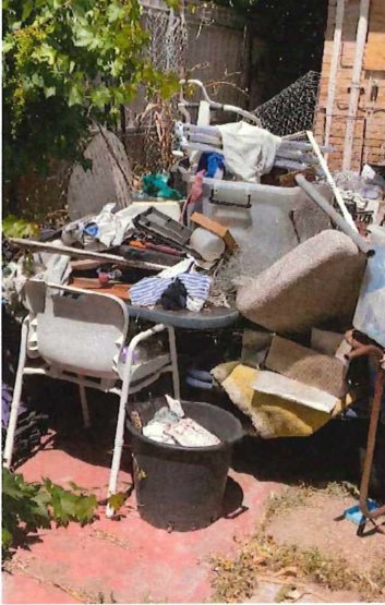 Backyard piled with chairs, mattresses and household waste before clean-up