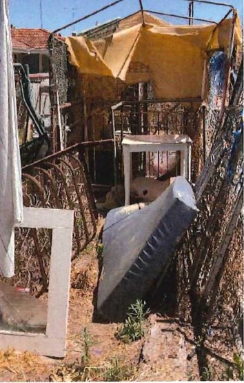 Backyard waste including a tarp-covered pile and rusted bedframe