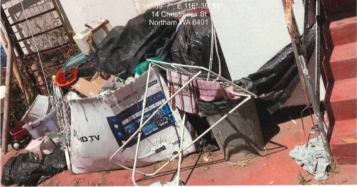 Wide view of backyard waste including a discarded TV and broken furniture